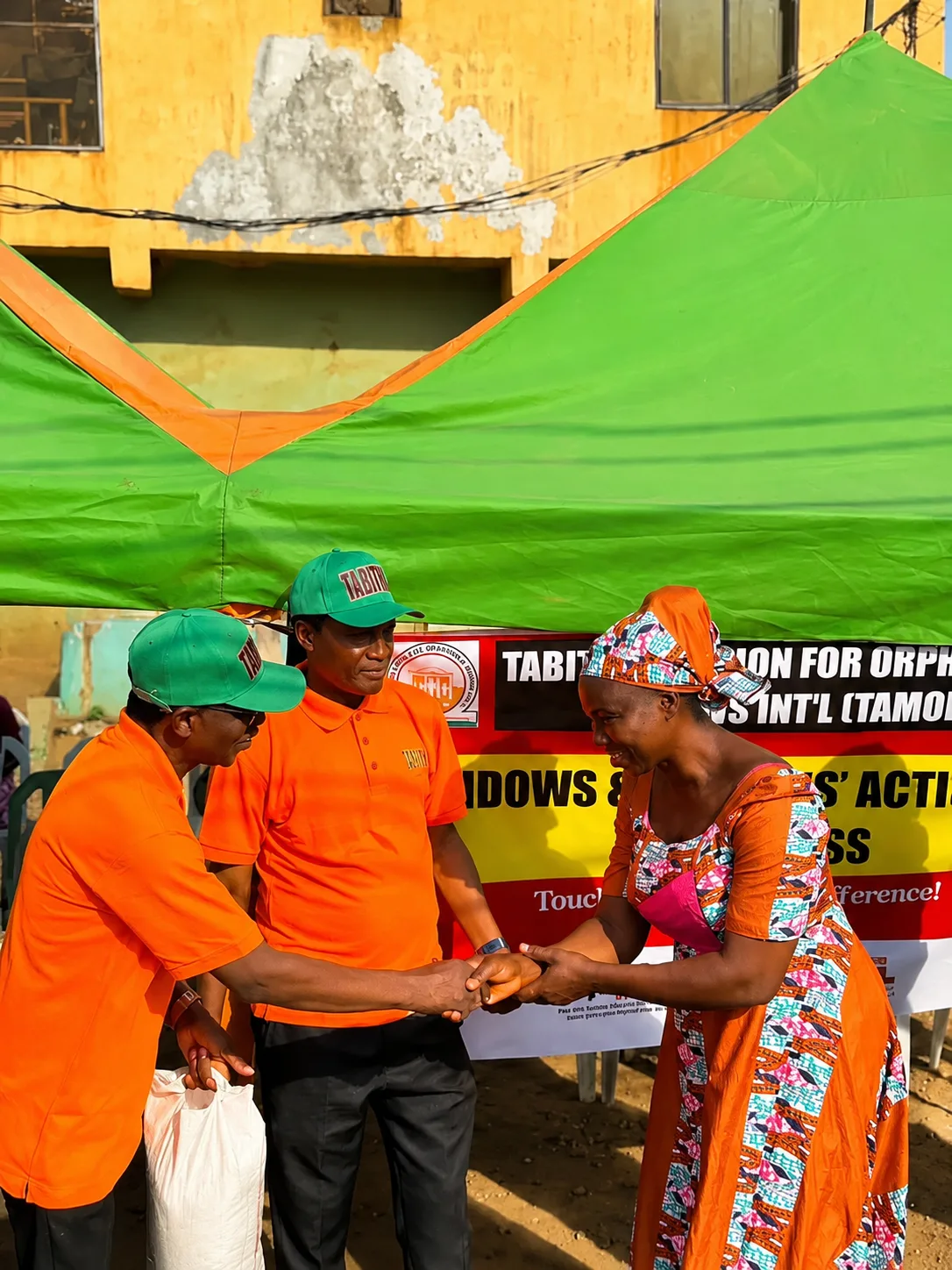 TAMOW volunteers greeting a beneficiary with a foodstuff donation
