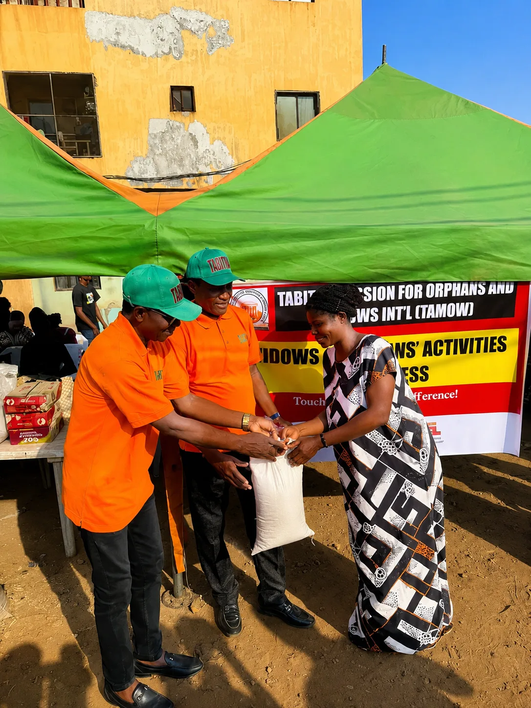 TAMOW volunteers handing a foodstuff sack to a beneficiary