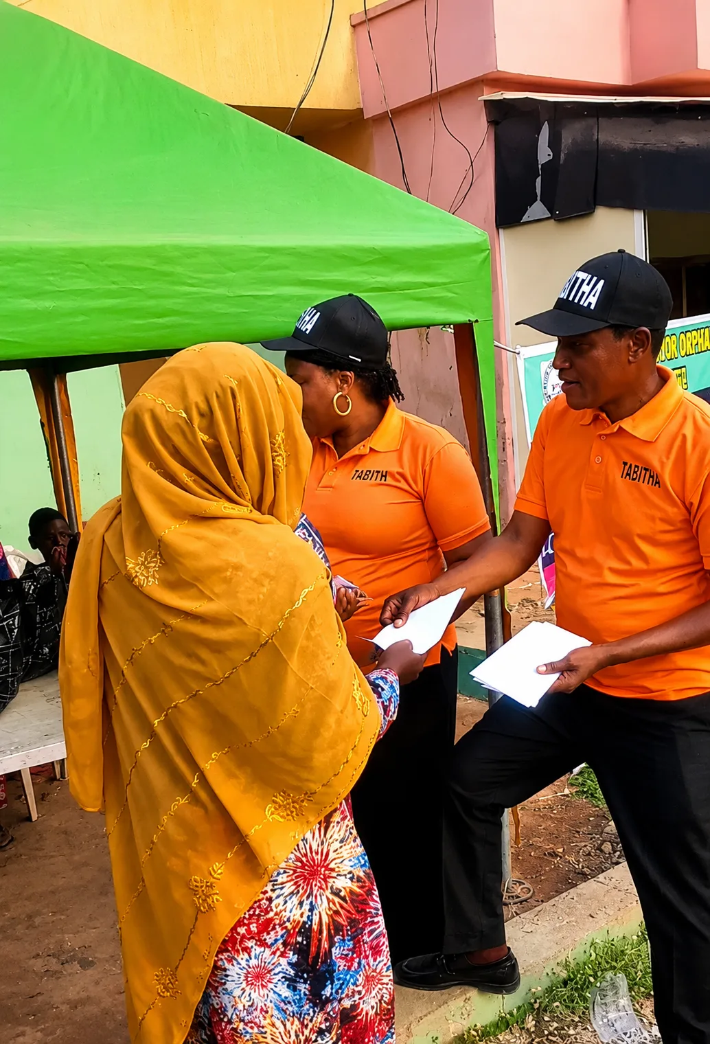 TAMOW staff handing a welfare envelope to a widow