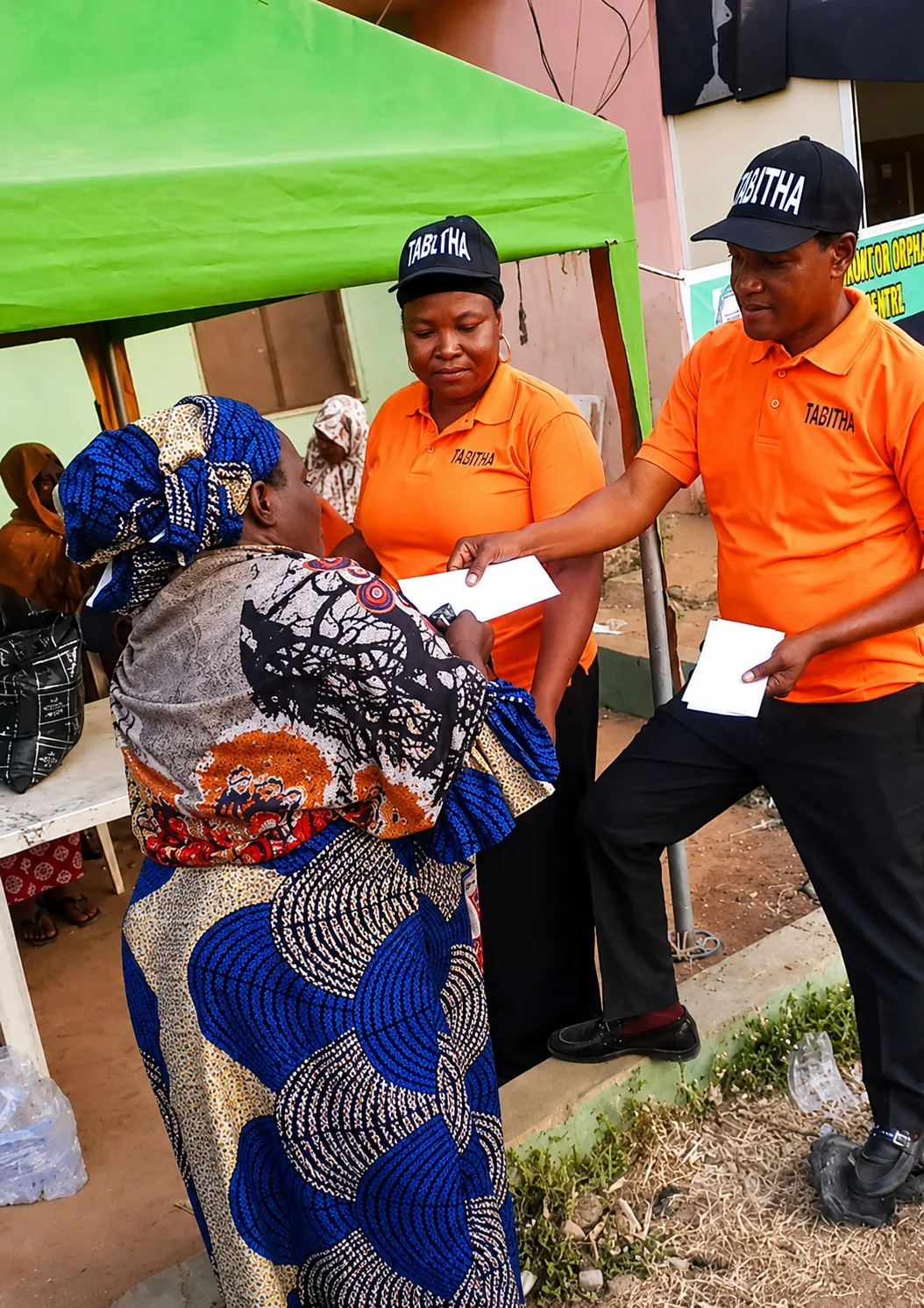 TAMOW staff handing a welfare envelope and package to a widow