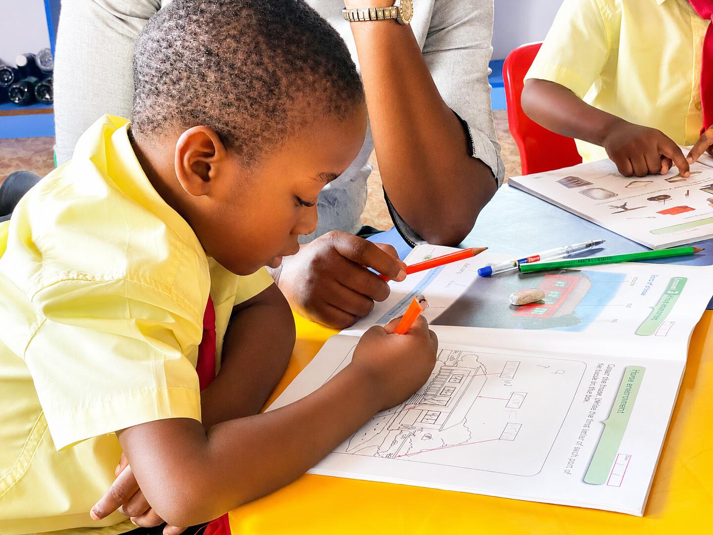 A pupil writing with guidance from an educator